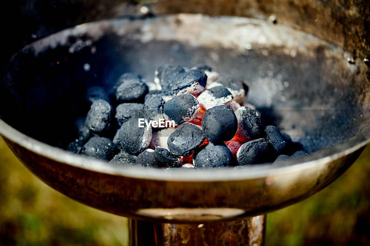 Closeup of glowing coal in metal grill on summer day in the garden