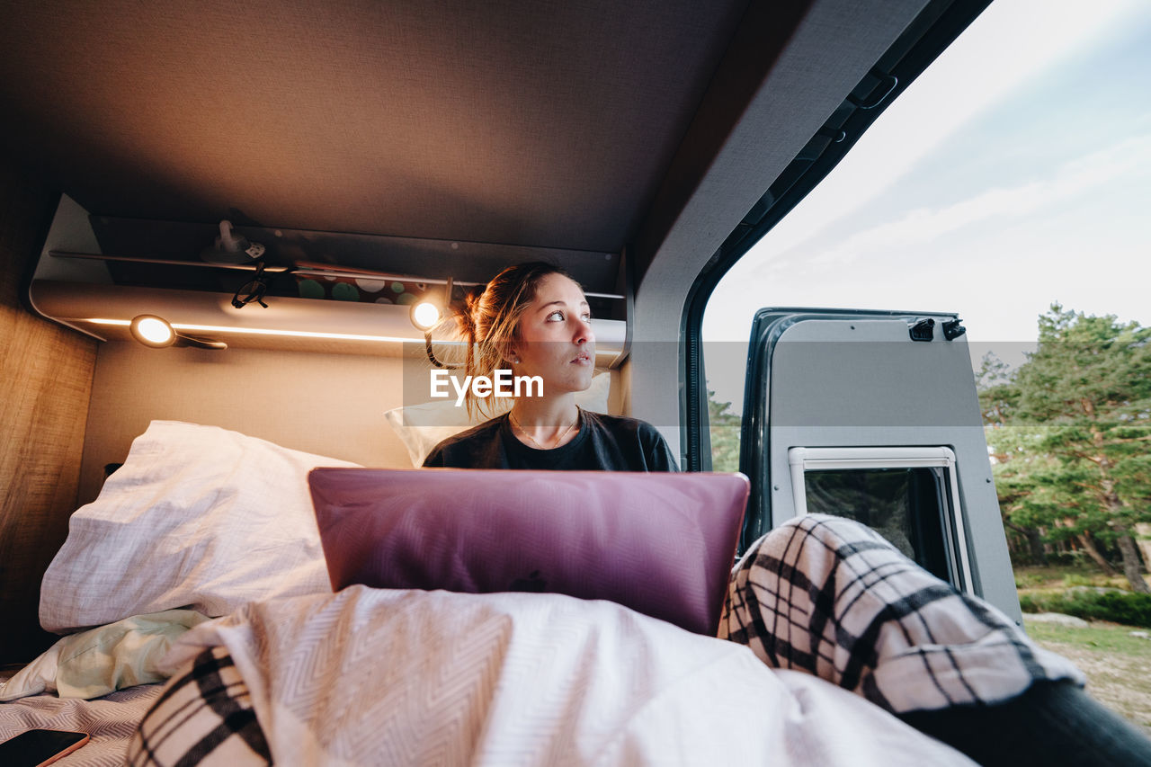 Young woman using laptop in camper