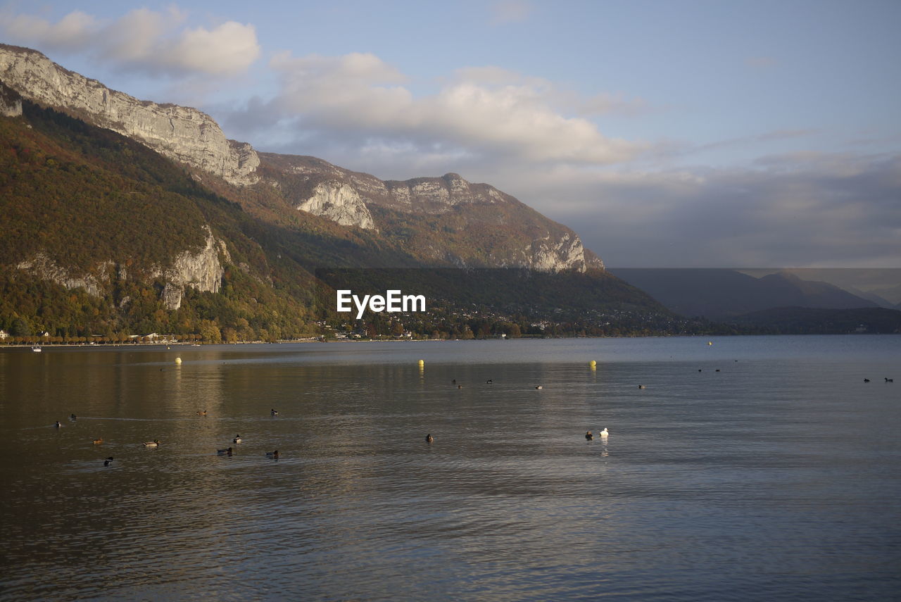 Scenic view of sea by mountains against sky