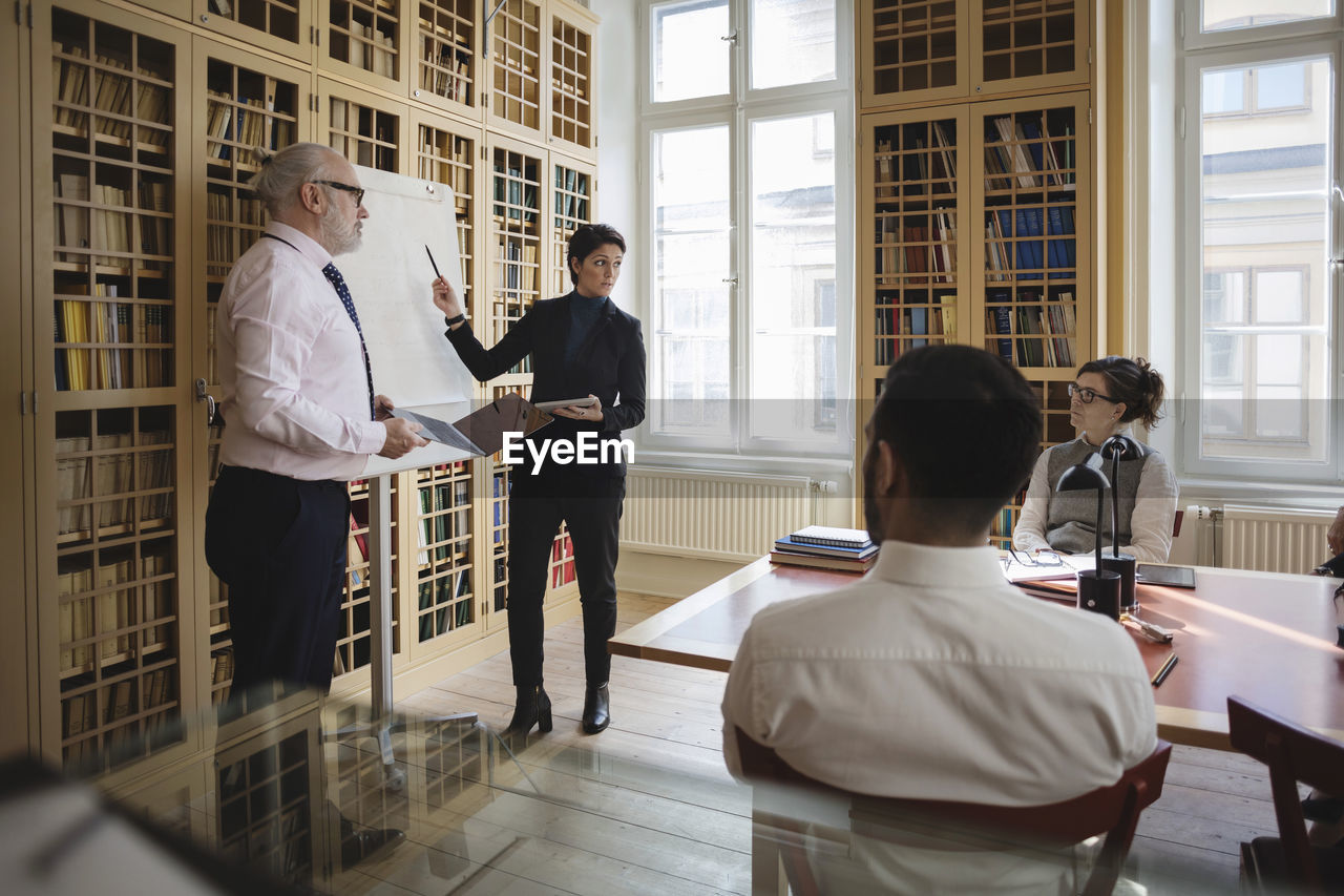 Male and female professionals giving presentation to coworkers in board room