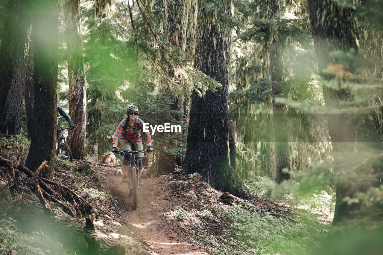 A young woman rides her ike through the forest at mt. hood, oregon.