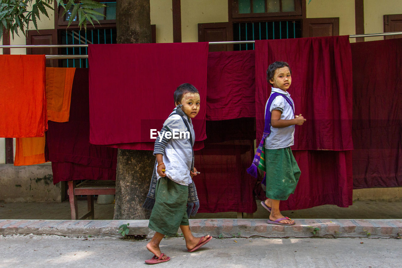 FULL LENGTH OF BOY WITH RED UMBRELLA ON STREET