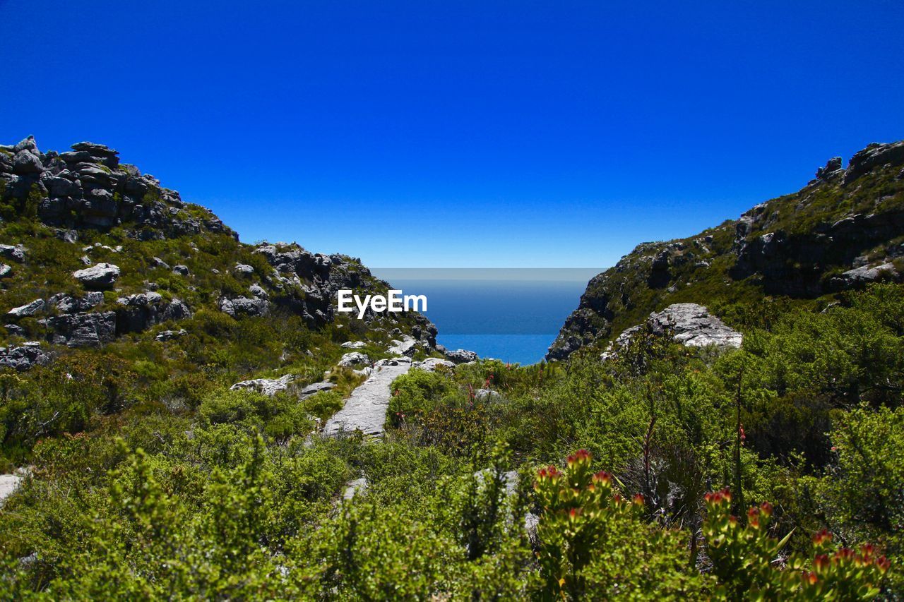 Scenic view of mountains and sea against clear blue sky