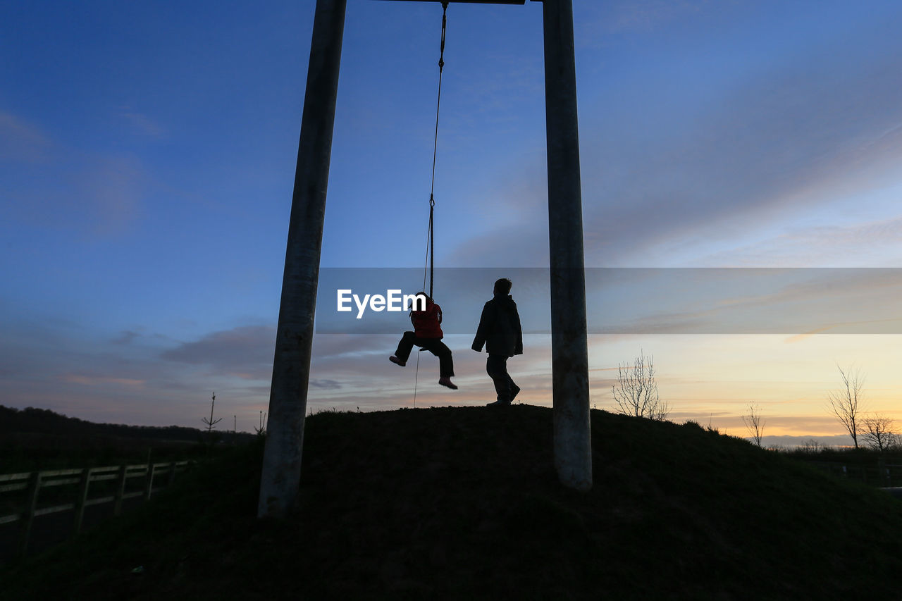 Low angle view of friends playing on hill during sunset