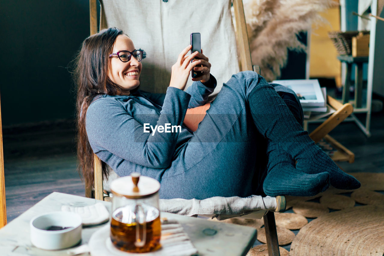 Woman using mobile phone while sitting on chair