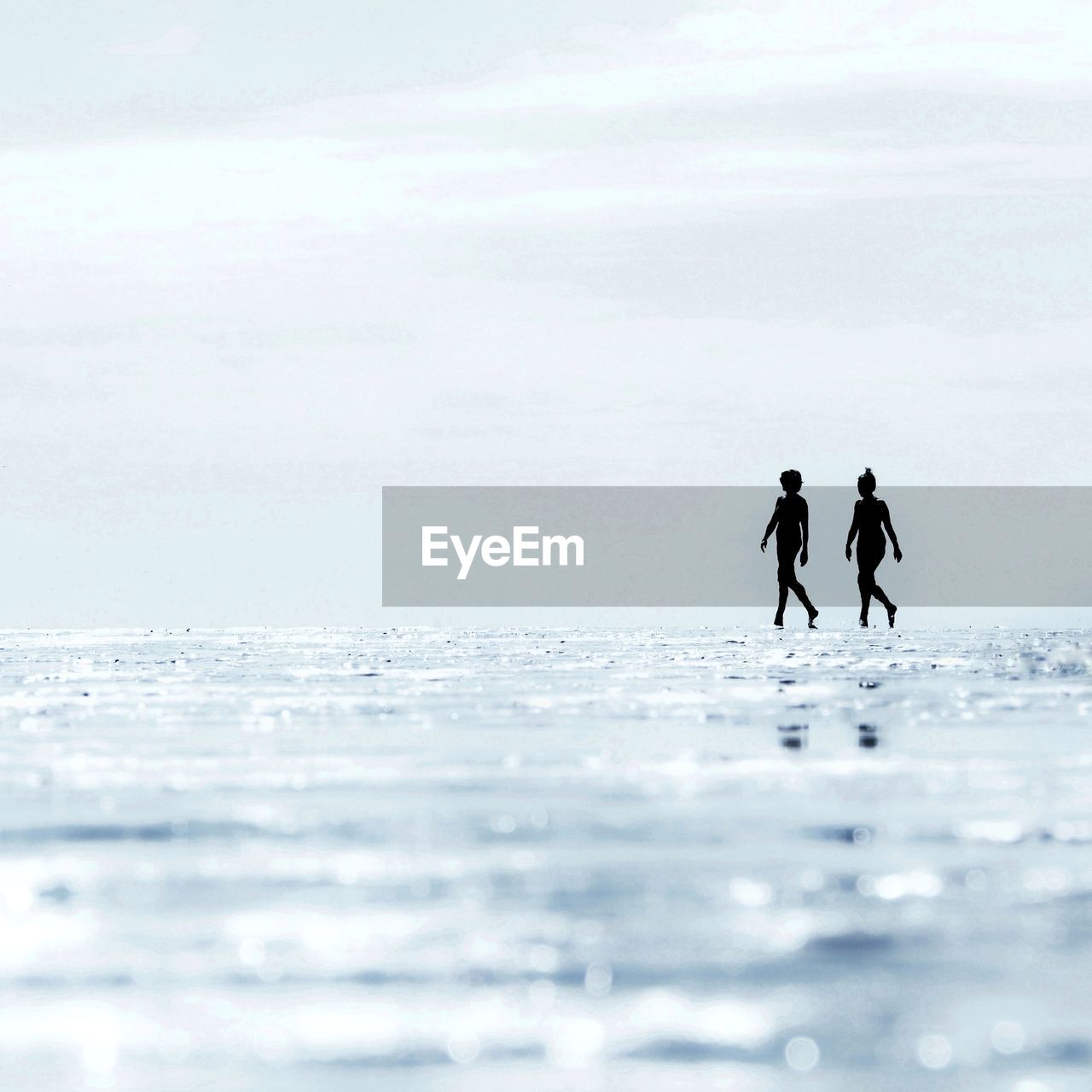 2 woman silhouettes walking on the beach during low tide