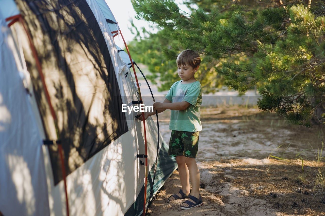 Cute little caucasian boy helping to put up a tent. family camping concept