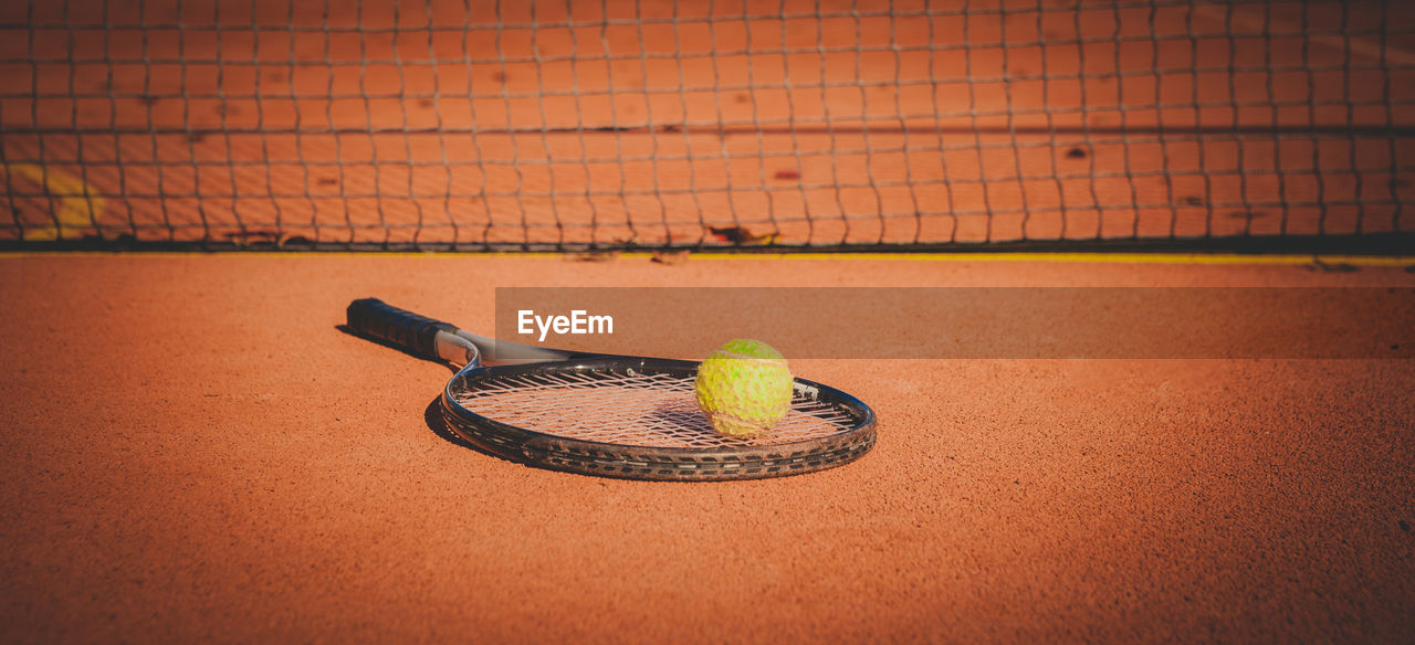 Close-up of tennis ball and racket on court