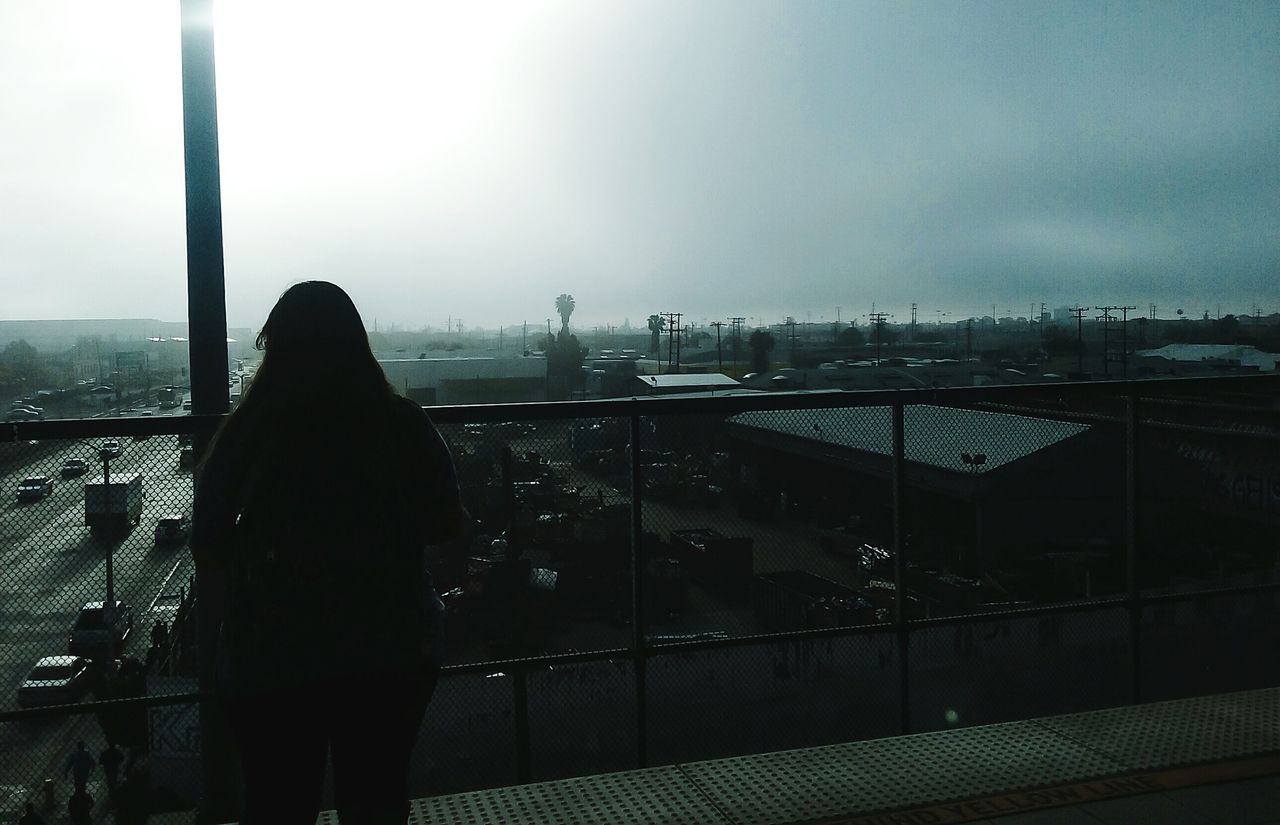 Rear view of woman standing in balcony against sky on sunny day