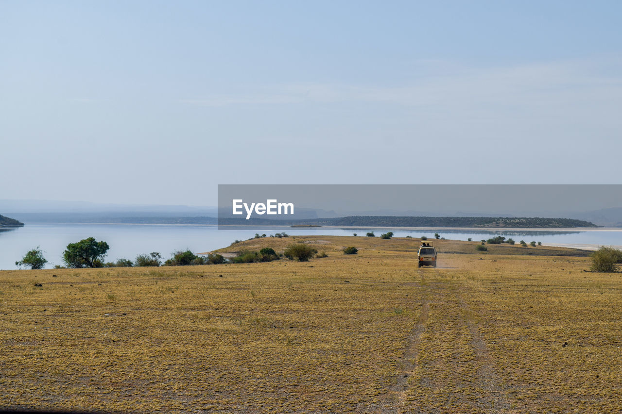 Safari van driving against scenic lake at lake magadi 