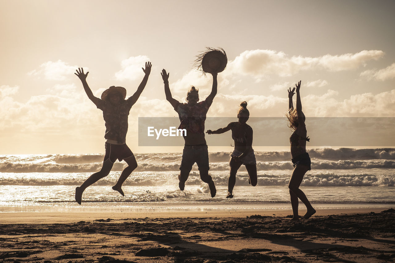 Cheerful friends enjoying on beach during sunset