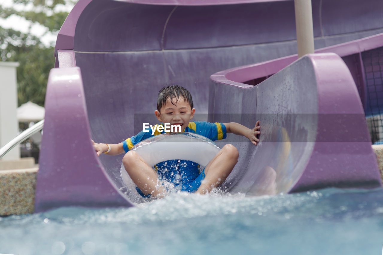 Boy sliding down in water slide at water park