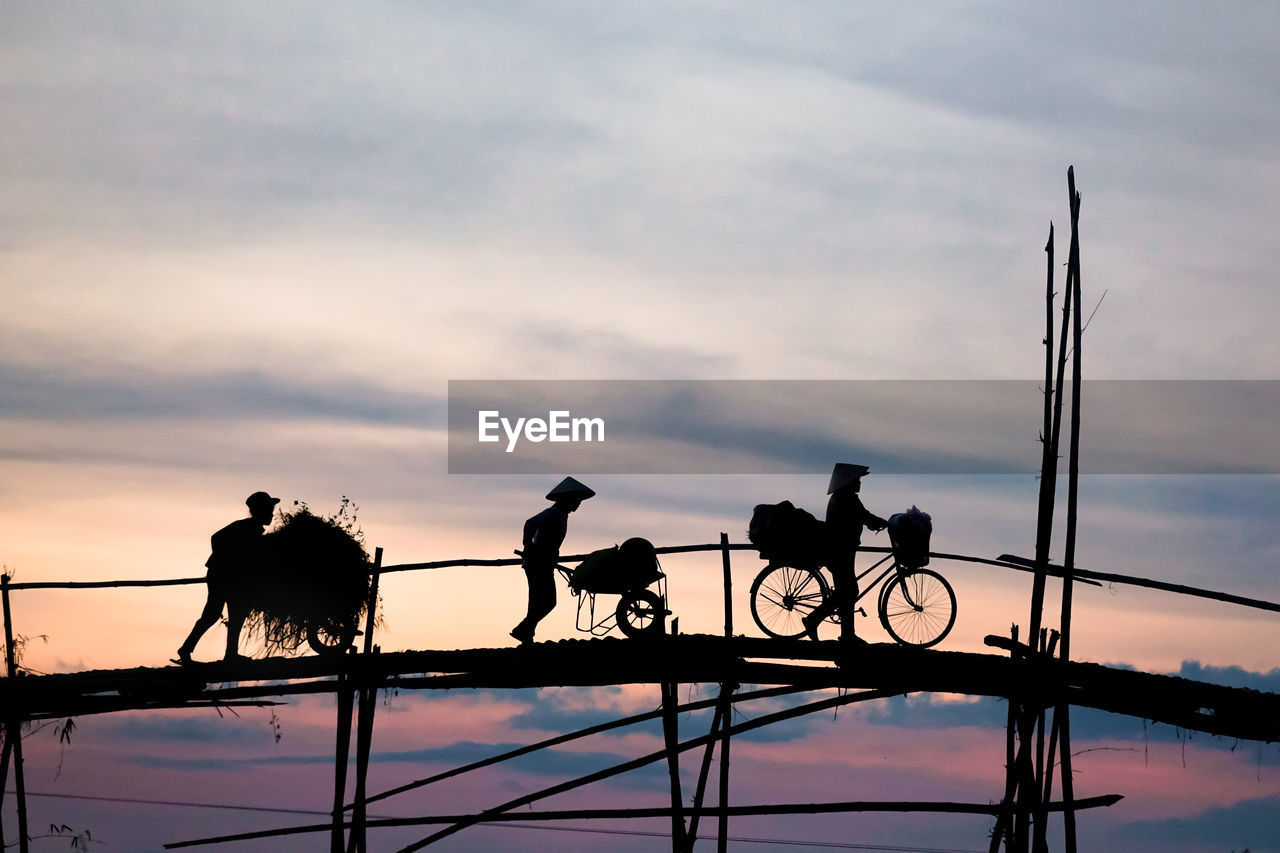 SILHOUETTE MAN RIDING BICYCLE ON BRIDGE AGAINST SKY