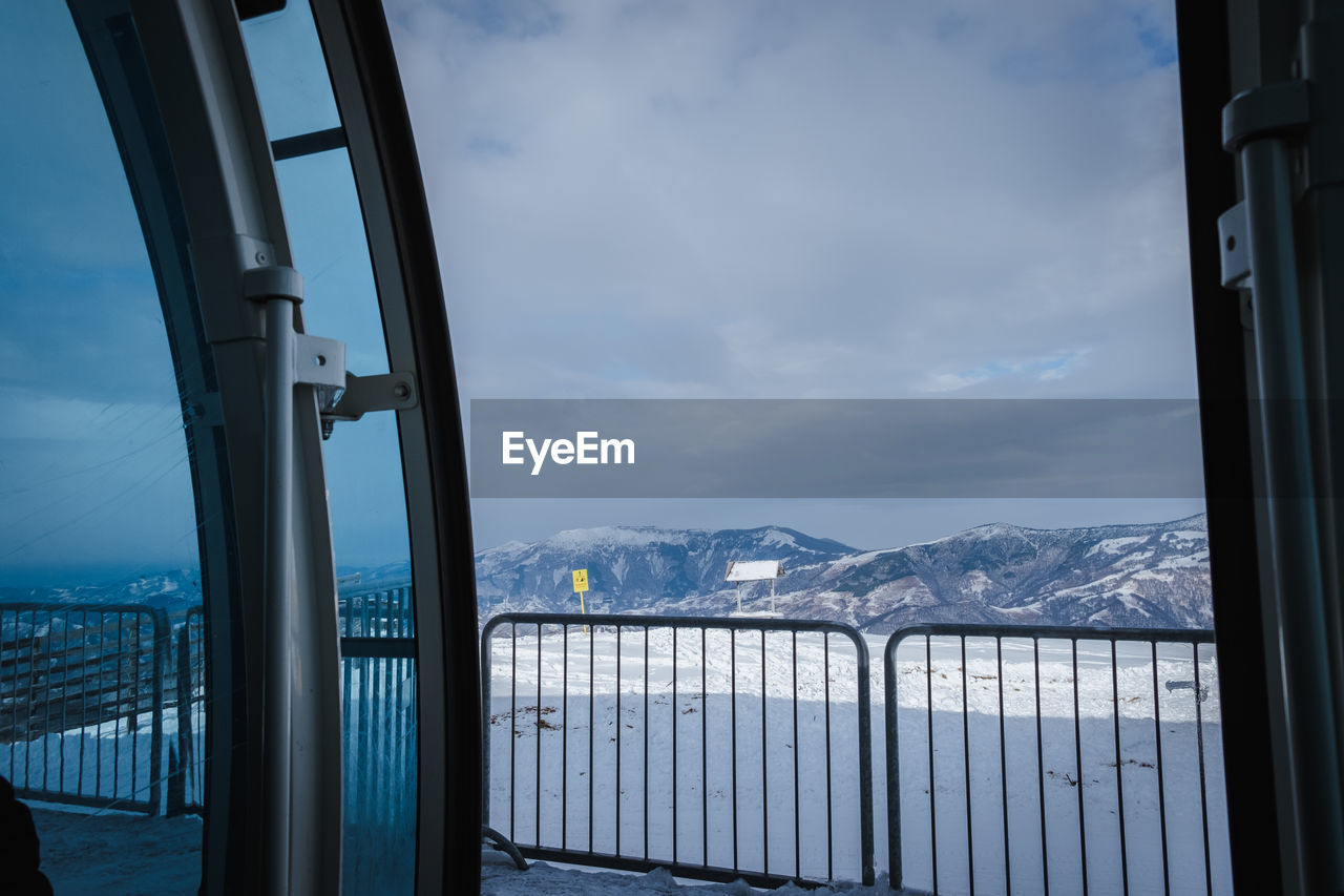 SCENIC VIEW OF SNOWCAPPED MOUNTAIN AGAINST SKY SEEN THROUGH WINDOW