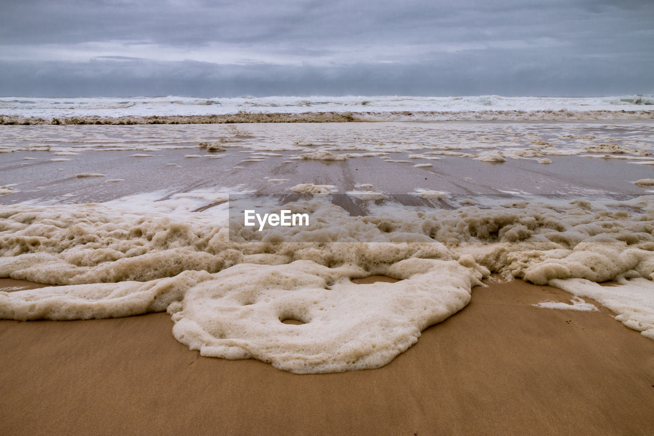 ROCKS ON BEACH AGAINST SKY