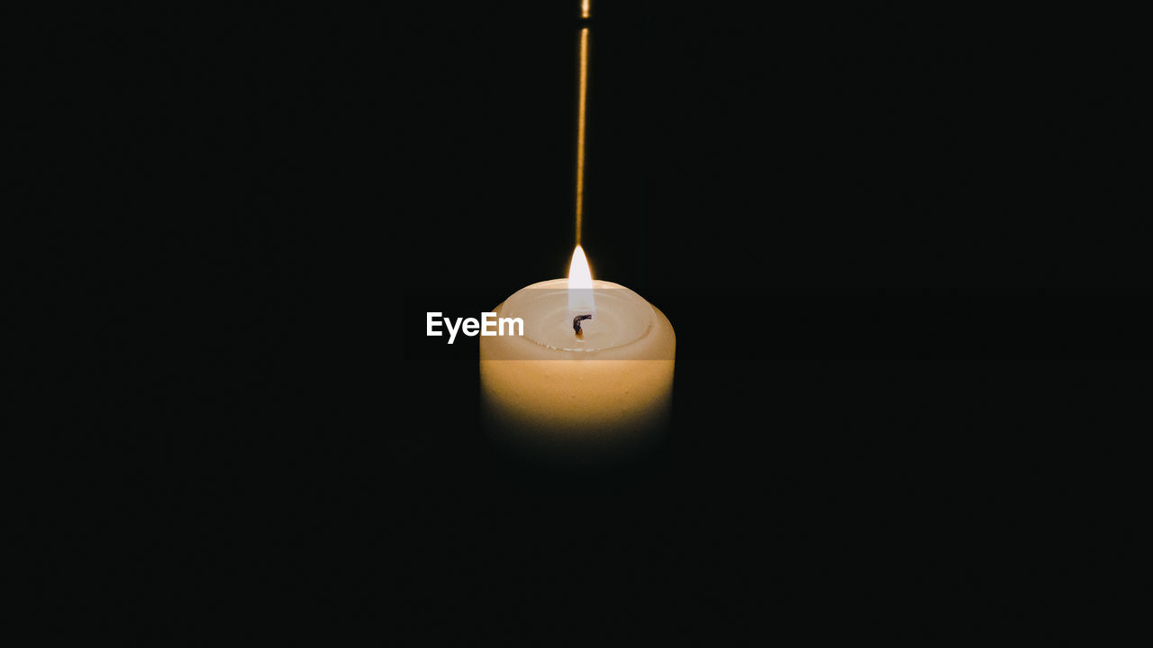 Close-up of illuminated candle against black background