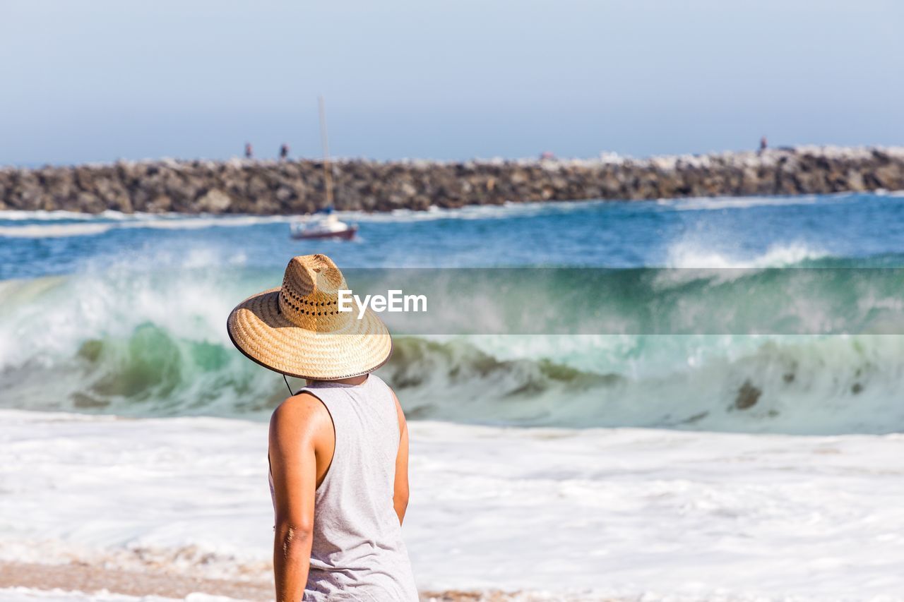 Side view of woman standing on beach against clear sky