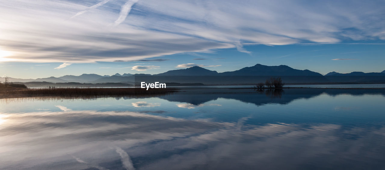 Scenic view of lake chiemsee by mountains against sky