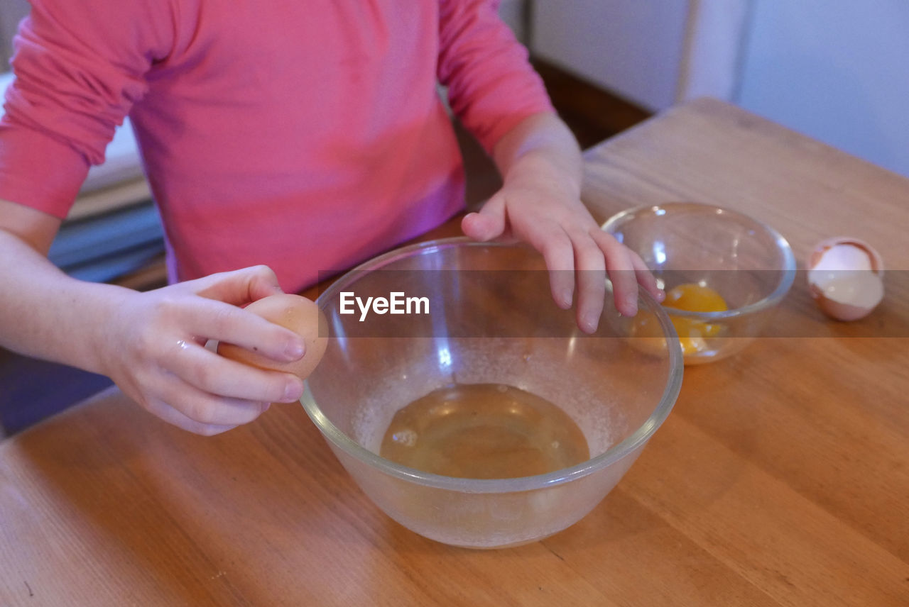 Close-up of girl separating yolk and egg on table