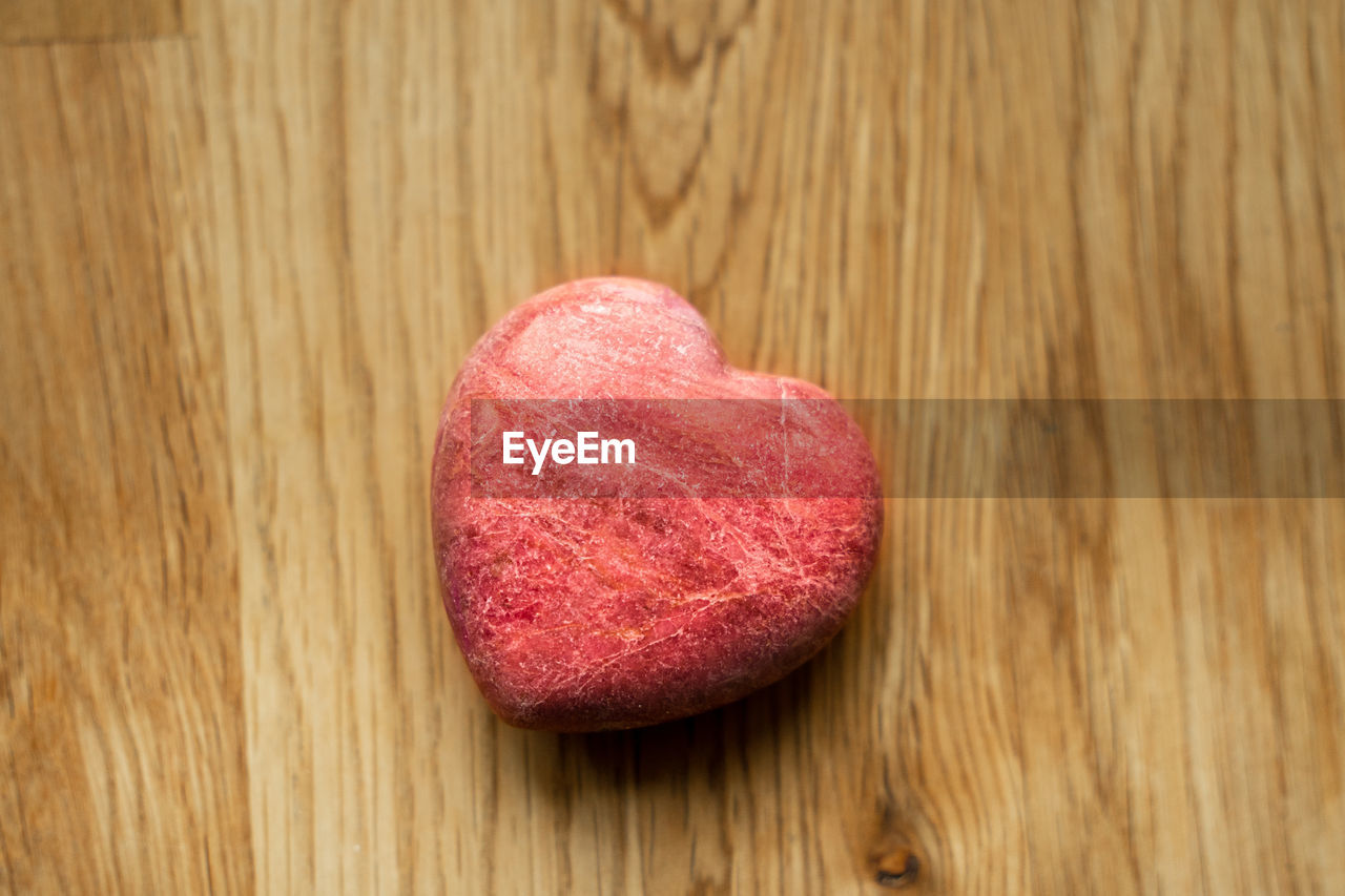 Stone heart on wooden background with natural light