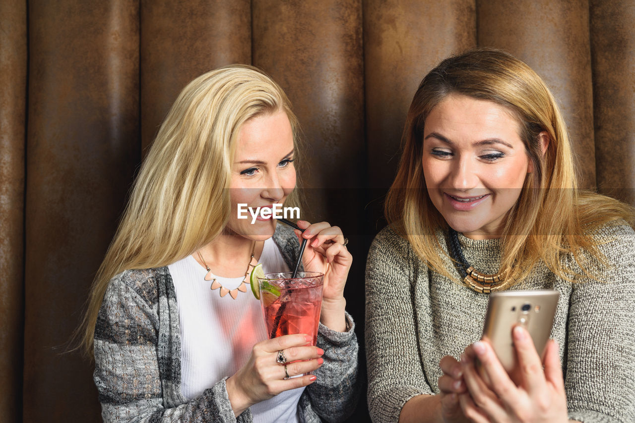 Happy women using smartphone in pub