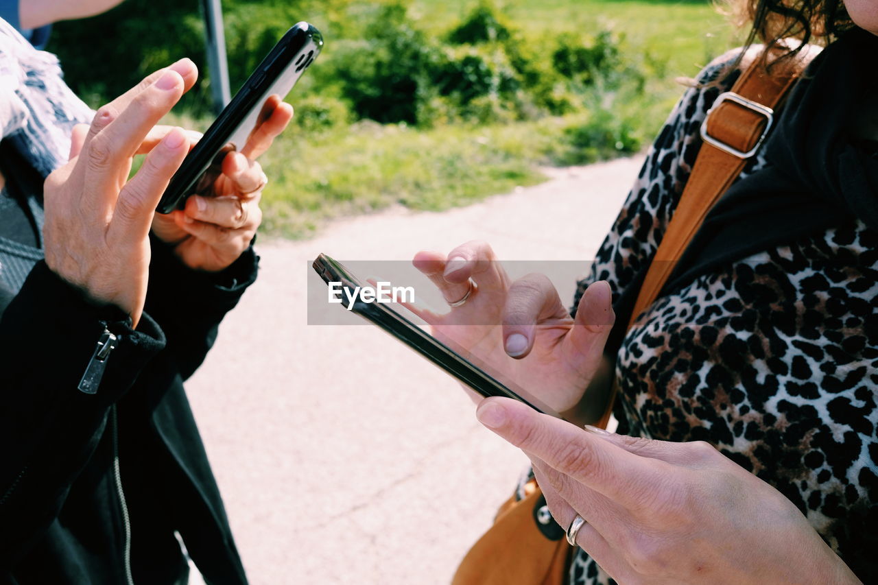 Midsection of man and woman using smart phone