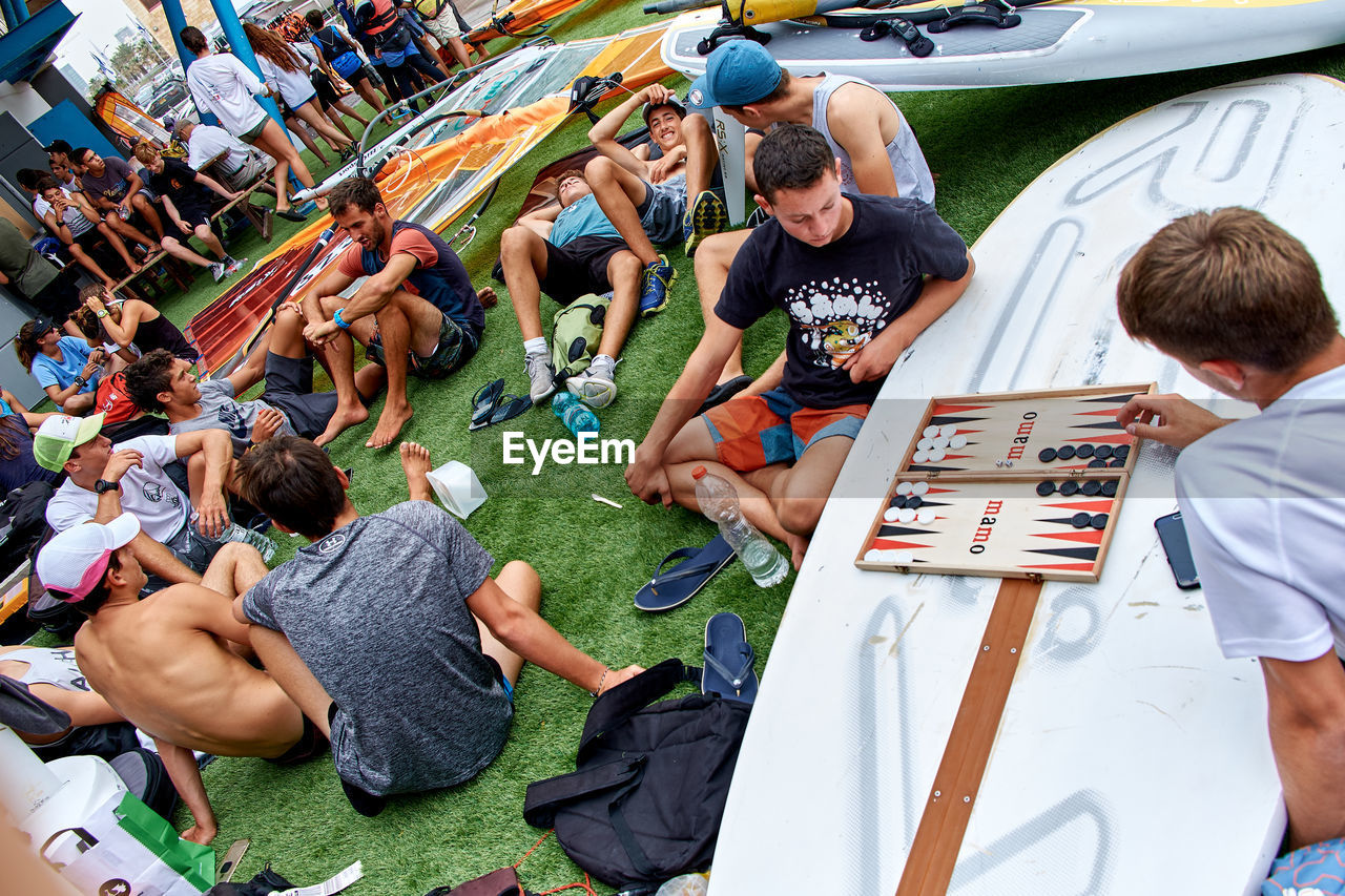 HIGH ANGLE VIEW OF GROUP OF PEOPLE SITTING IN A ROW