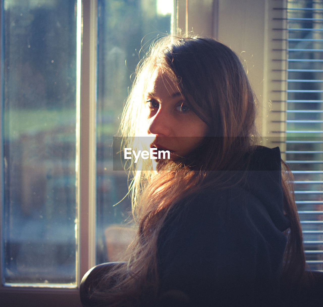 Side view of young woman standing by window