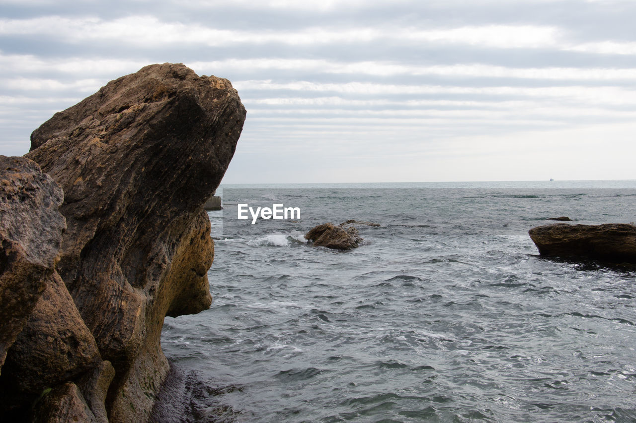 Rock formation by sea against sky