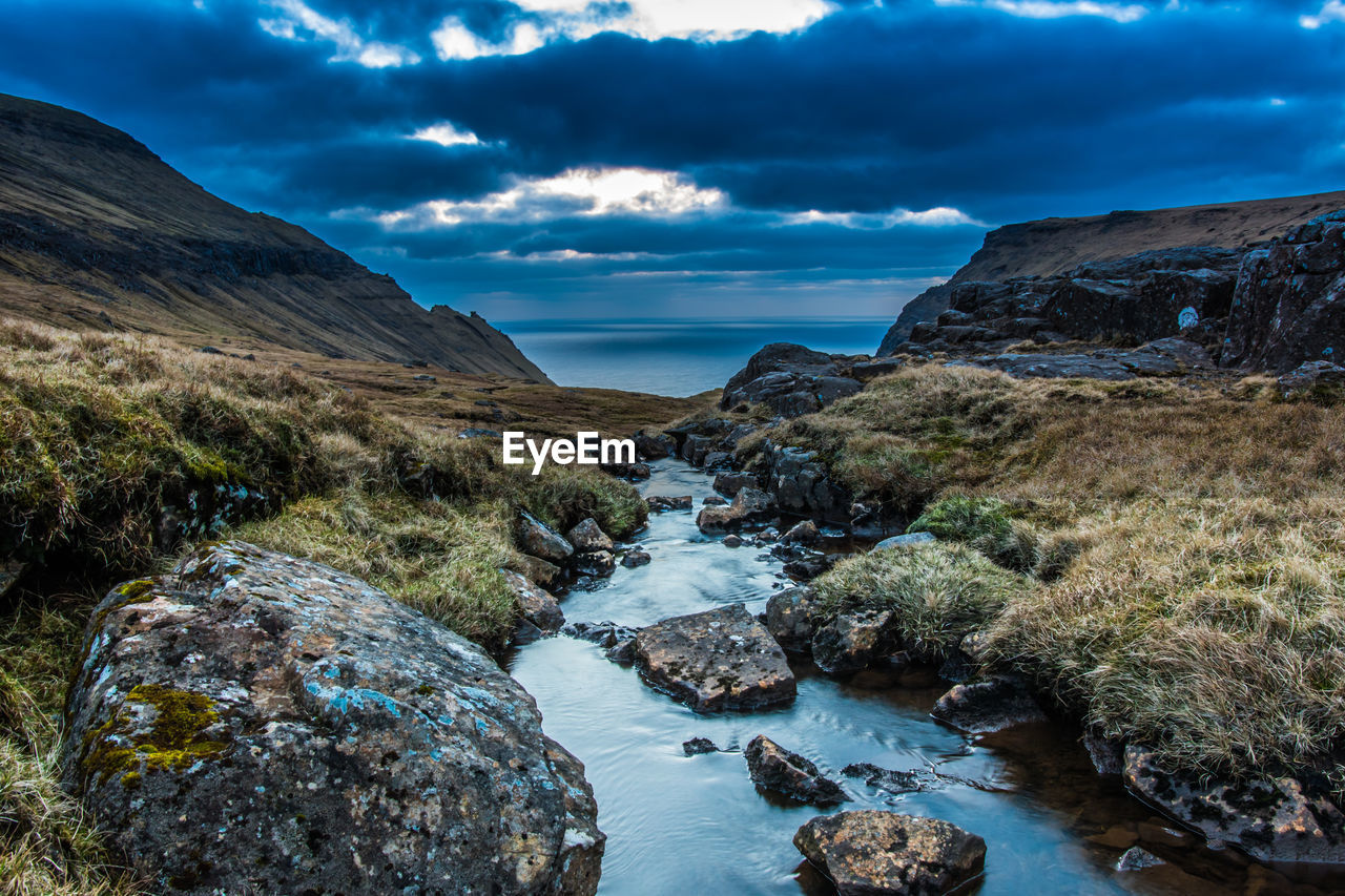 A narrow water channel in the mountain field against a cloudy sky. high quality photo