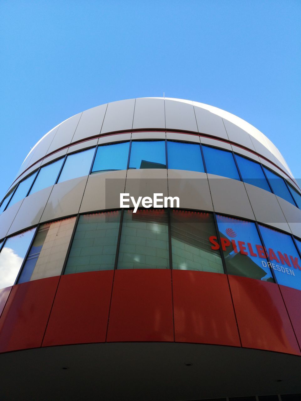 LOW ANGLE VIEW OF MODERN GLASS BUILDING AGAINST BLUE SKY