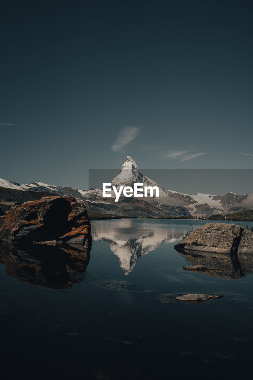 Scenic view of lake by snowcapped mountain against sky