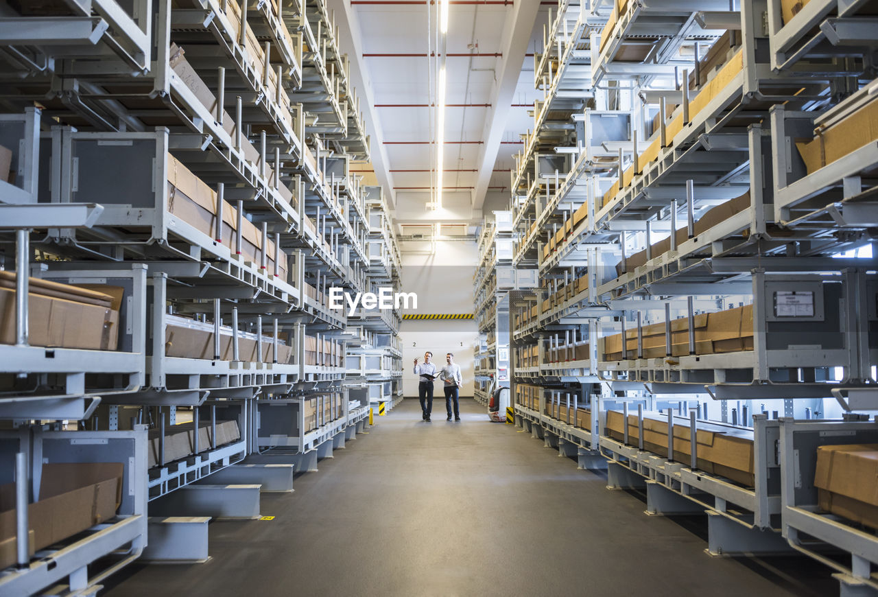 Two men walking in factory warehouse