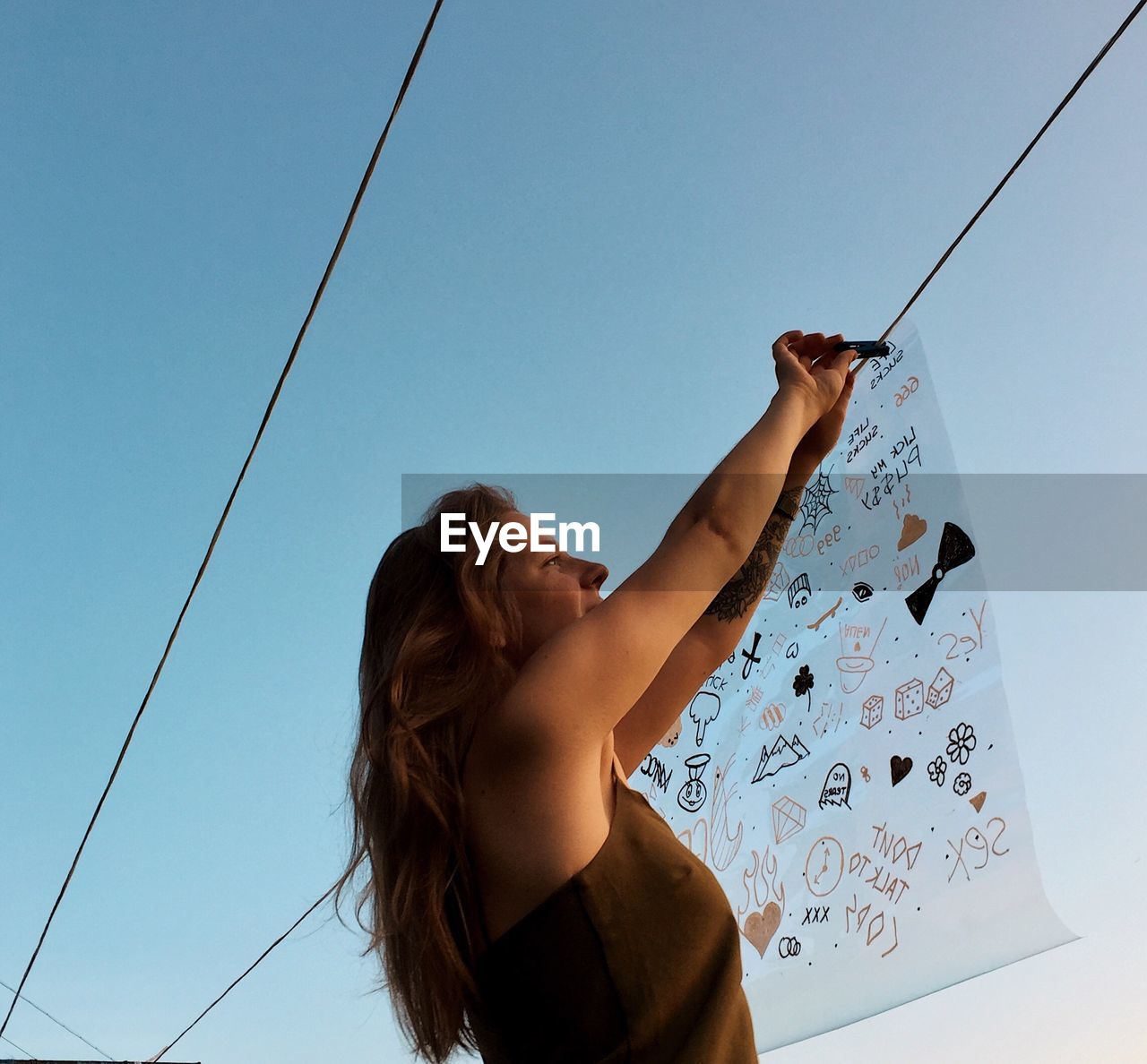 Low angle view of woman standing against clear sky