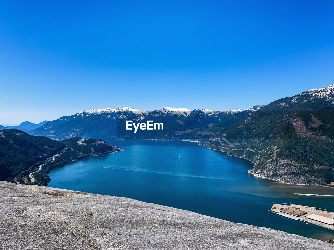 SCENIC VIEW OF LAKE BY MOUNTAIN AGAINST CLEAR BLUE SKY