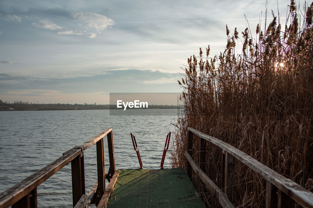 WOODEN PIER OVER LAKE AGAINST SKY