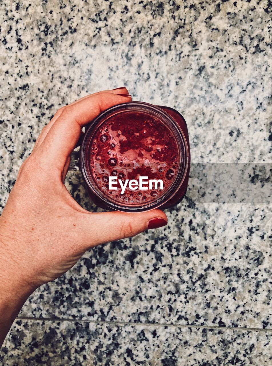 Cropped hand of woman holding smoothie in jar