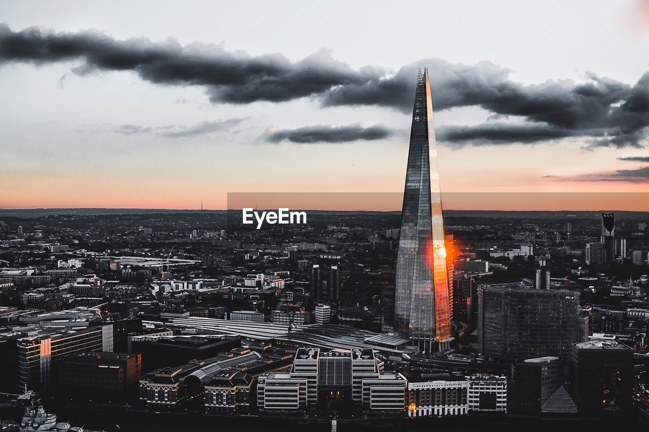 HIGH ANGLE VIEW OF ILLUMINATED CITYSCAPE AT SUNSET