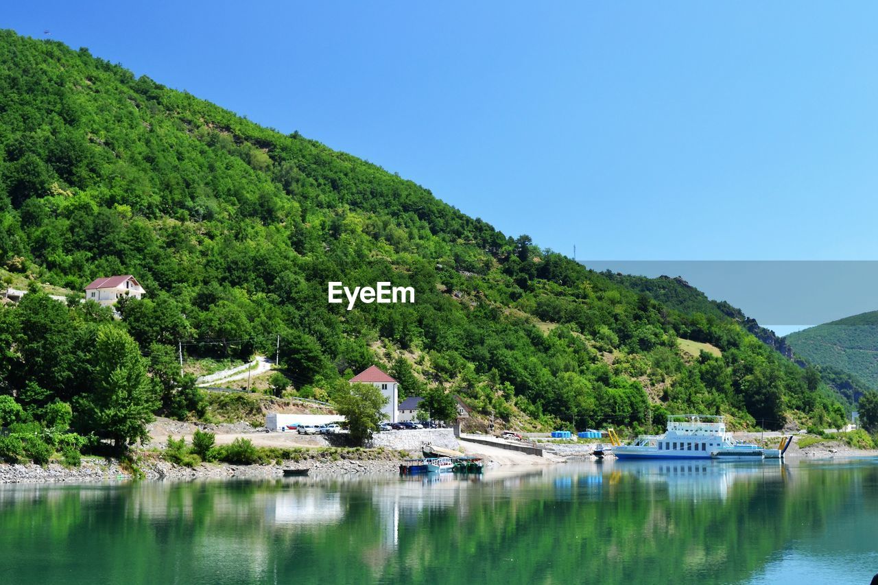 Scenic view of lake and mountains against clear blue sky