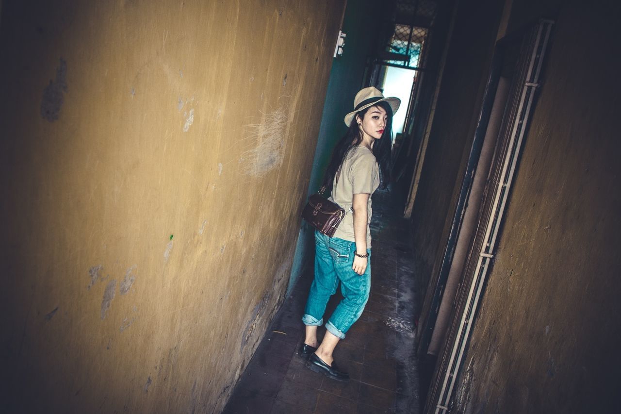 FULL LENGTH PORTRAIT OF YOUNG WOMAN STANDING ON WALL