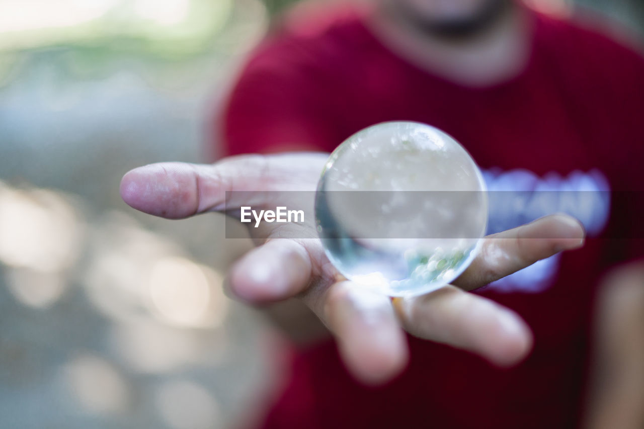 Midsection of man holding crystal ball