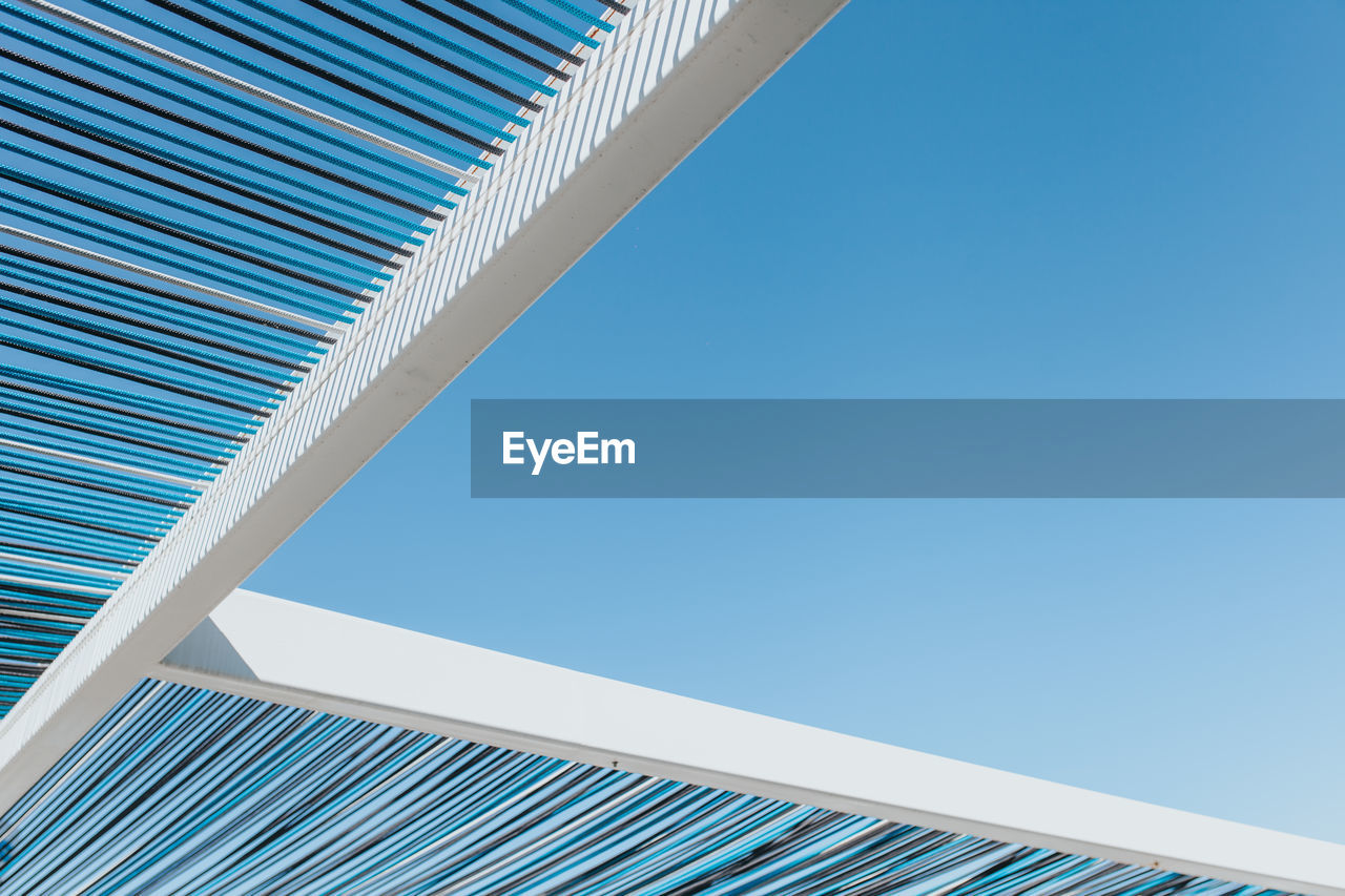 Low angle view of shade structure against clear blue sky