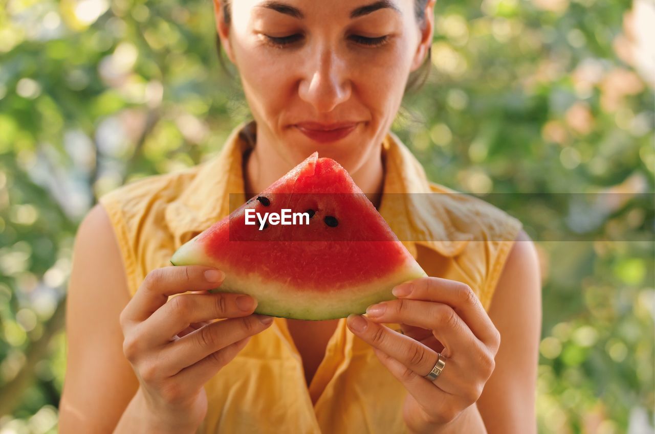 Smiling young woman holding watermelon slice