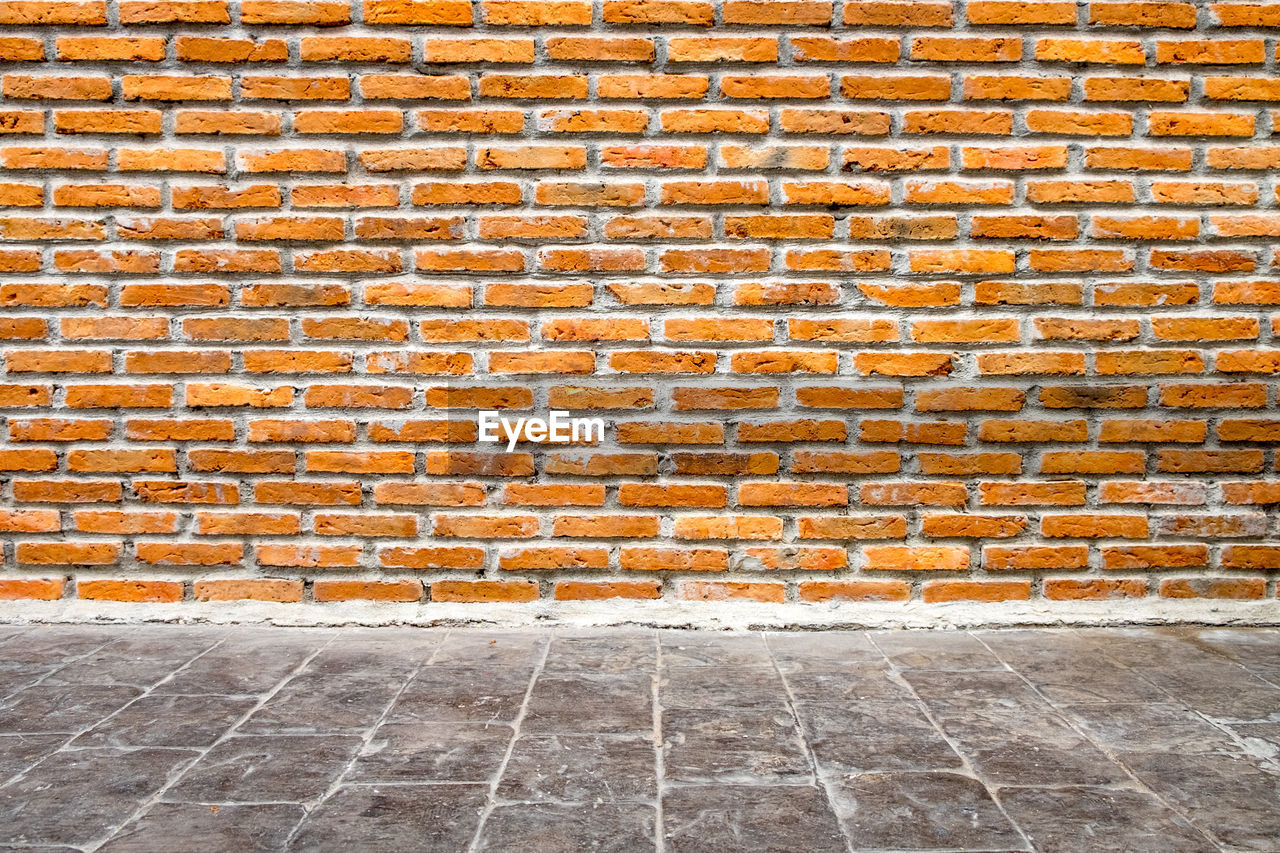 Empty footpath against brick wall