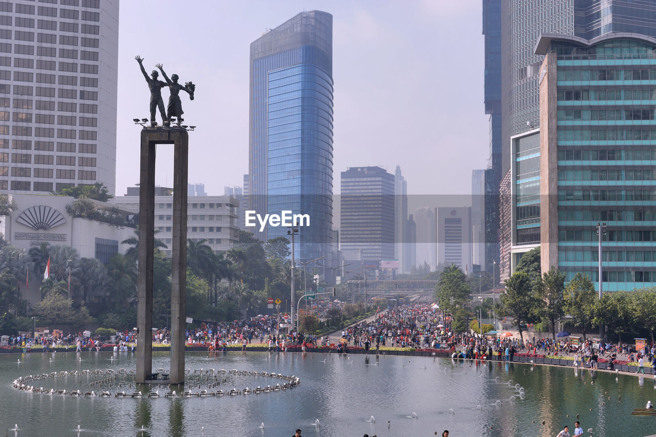 City buildings by river against sky