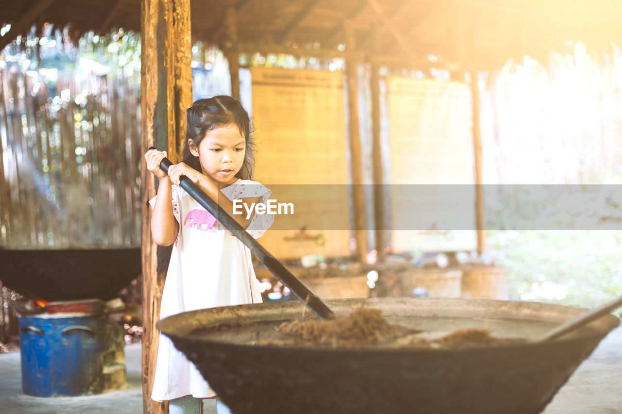 Girl mixing animal dung in container at workshop