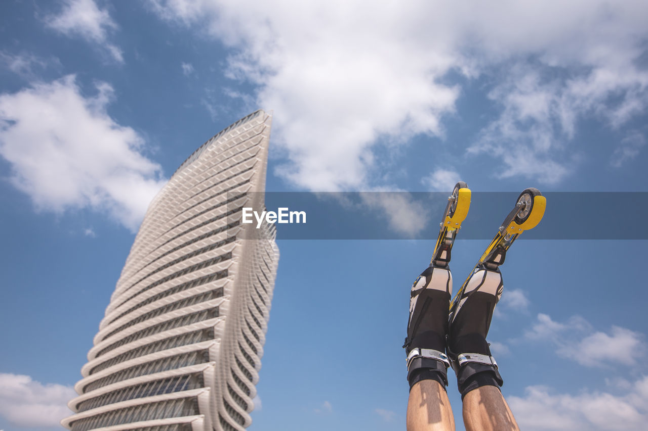 Low section of man with inline skates against blue sky