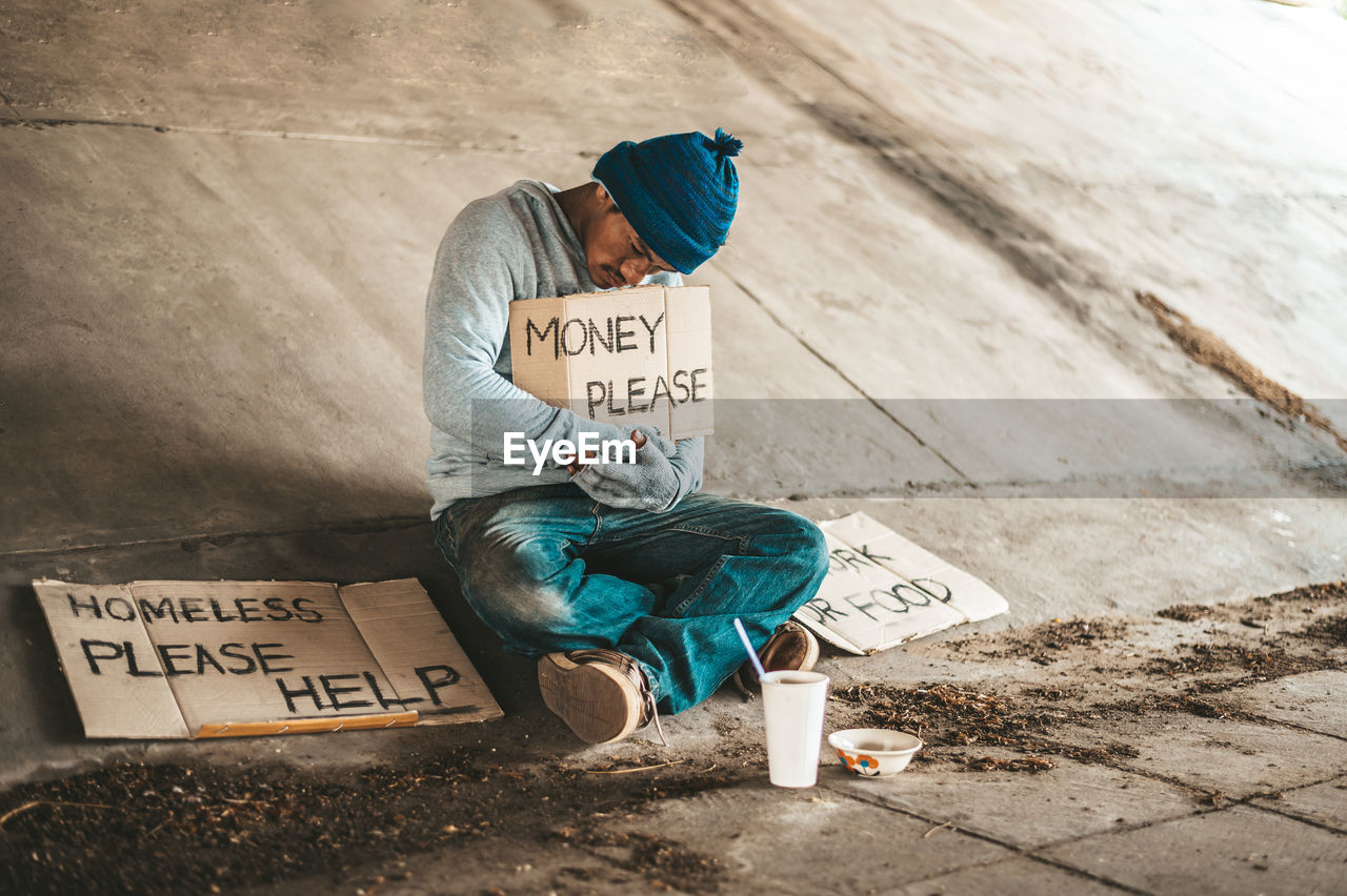 REAR VIEW OF MAN SITTING ON SEAT AT SIGN