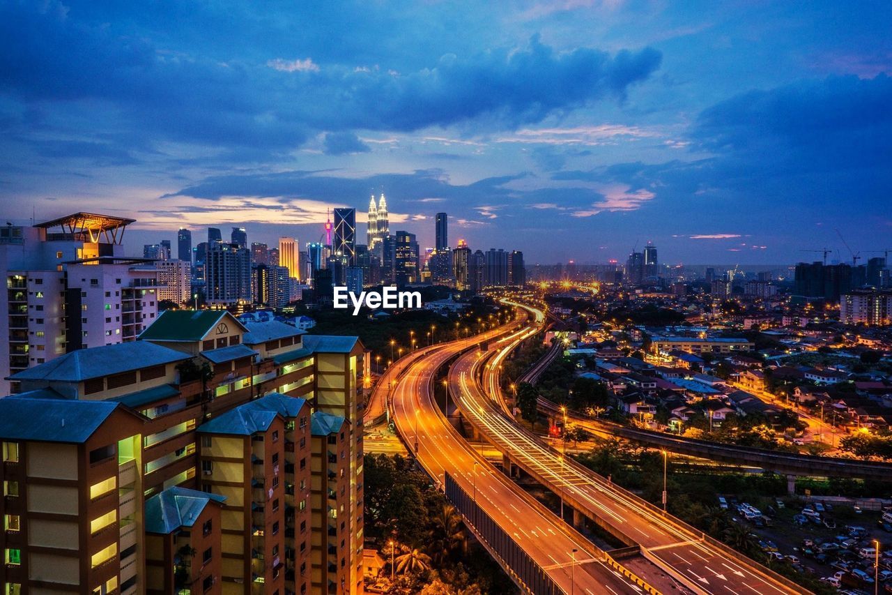 Distant view of petronas towers against sky in city at dusk