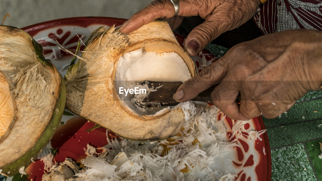 Close-up of hands scraping coconut with tool